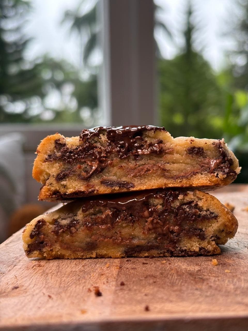 two halves of a brune cookie stacked on a wooden board, chocolate melting